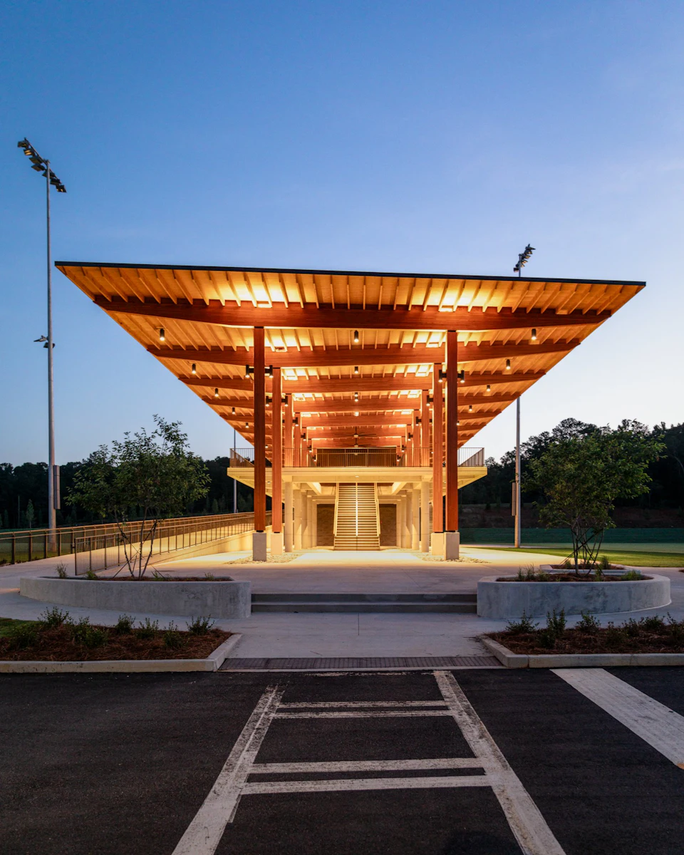 View beneath the long timber observation canopy beside the soccer training fields at dusk.