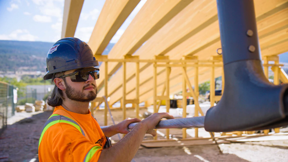 Worker fitting a stair component beneath the hangar roof