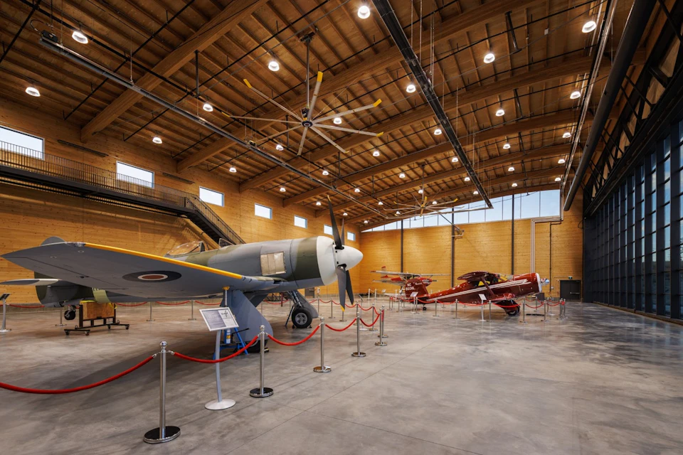 Open exhibit hall beneath exposed timber at KF Aerospace Centre