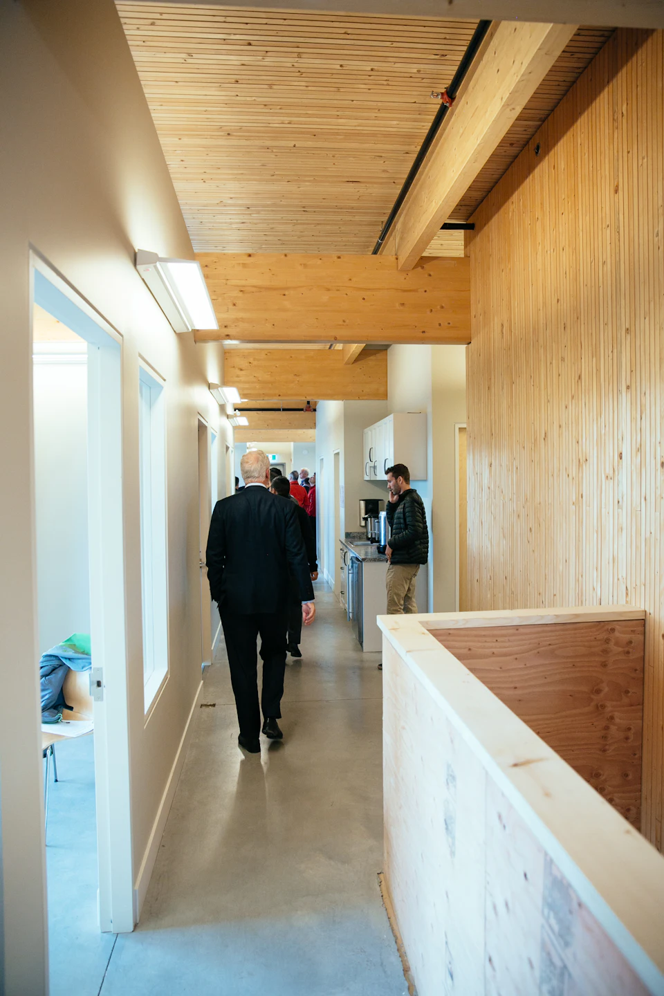 People walking through a wood-lined corridor at StructureCraft Headquarters